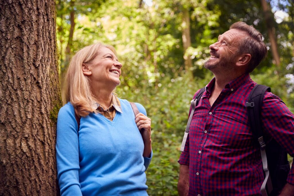 Mature couple in countryside hiking along path through forest together