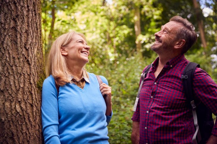 Mature couple in countryside hiking along path through forest together